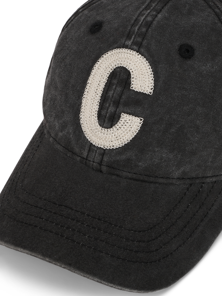 Schwarze Cap in verwaschener Optik mit einem großen, aufgestickten weißen Buchstaben „C“ auf der Front.