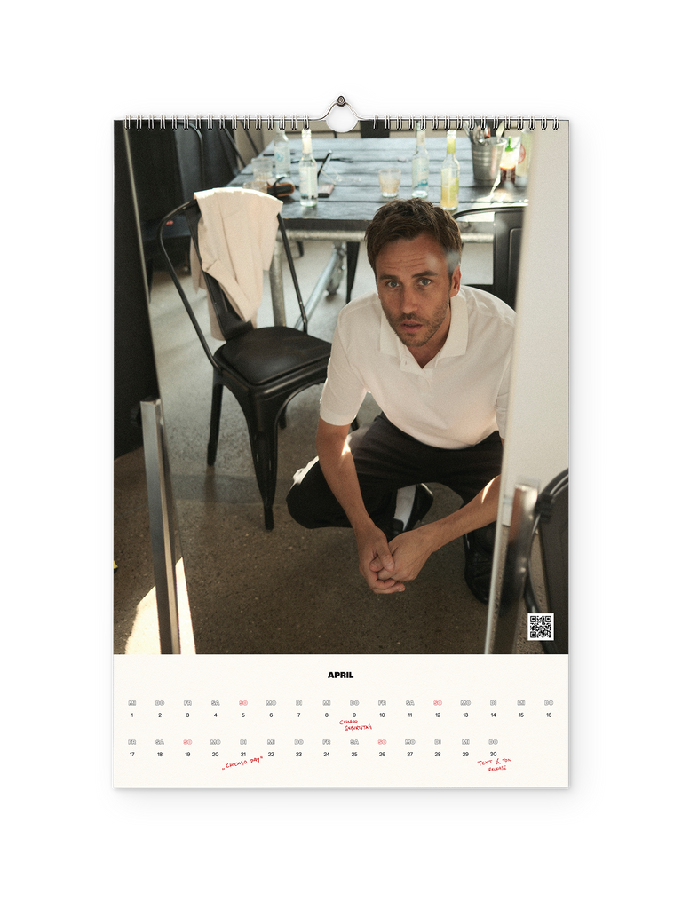 Monatsseite für April mit einem Foto von Clueso in weißem Polohemd, wie er kniend zwischen schwarzen Stühlen und einem Tisch mit Getränkeflaschen in die Kamera blickt. Unten ist der Monatskalender mit handschriftlich markierten Terminen wie „Ciao Gigetta“ und „Ciao Day“ zu sehen.